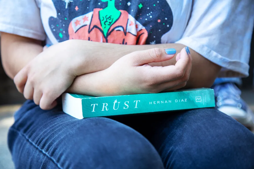 A student holds a copy of The Humanities Institute’s 2024 Deep Read selection, Hernan Diaz’s Pulitzer Prize–winning novel Trust. UCSC students explored the book and Diaz’s other writings in a course with Lecturer and THI Program Manager Laura Martin. Photo by Carolyn Lagattuta