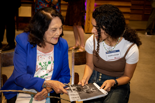 Dolores Huerta talks with a UCSC student and signs a copy of a historic photograph of Huerta speaking at a rally. UCSC is partnering with the Dolores Huerta Foundation to develop a new archive that will share writings, records, and artifacts from Huerta's activism. Photo: Devi Pride Photography