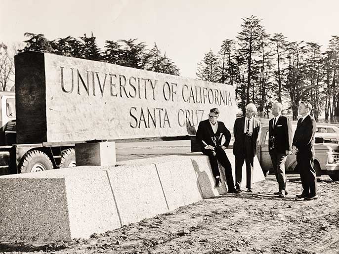 UC Santa Cruz’s founding chancellor, Dean McHenry, second from right, at the installation in 1966 of the original carved solid redwood sign that has defined the main campus entrance.